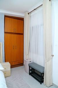 a bedroom with a bed and a window with a bench at Petite's Nest - Apartment 5 in Accra