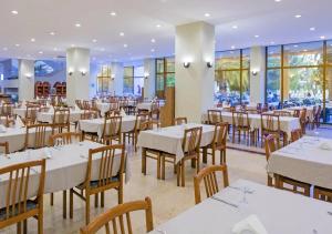 a restaurant with white tables and chairs and windows at Özkaymak Incekum Resort - Ultra All Inclusive in Avsallar