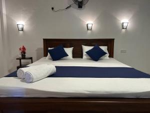 a large bed with blue and white sheets and pillows at Looma House Hiriketiya in Dickwella +7 photos