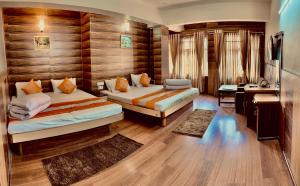 a hotel room with two beds and a desk at Hotel Marvel International And Restaurant in Darjeeling