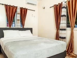 a bedroom with a bed with orange curtains at Bougan Villa in Brufut