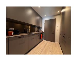 a kitchen with white cabinets and a door to a hallway at Zuhause am Bodensee in Bottighofen +3 photos