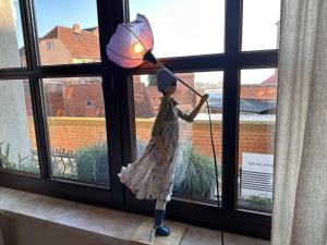 a doll holding a umbrella in a window at Ferienhaus Elbblick in Tangermünde