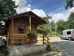 a small wooden cabin with a table and a van at Camp Litomerice in Litoměřice