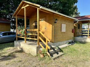 a small wooden house with a porch and a car at Camp Litomerice in Litoměřice