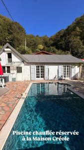 a house with a swimming pool in front of a house at Le Voile de la Mariée in Salazie