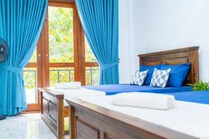 a bedroom with two beds with blue curtains and a window at Ella Flower Zone Holiday Resort in Bandarawela