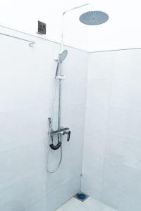 a shower in a white tiled bathroom at Ella Flower Zone Holiday Resort in Bandarawela