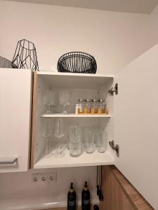a shelf with glasses and bottles on it in a kitchen at Gemütliches Apartment in Kehl am Rhein +14 photos