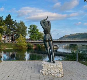 Eine Statue einer Frau, die auf einem Felsen neben einem Fluss steht in der Unterkunft Apartman Mila in Bihać