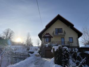 a house covered in snow with the sun in the background at Dom pod Jaworem in Rajcza