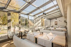 a restaurant with tables and chairs and large windows at Engel Gourmet&Spa in Nova Levante