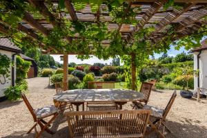 a patio with a table and chairs under a pergola at Orchard Paddocks in Guildford