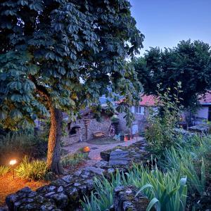 a garden with a tree and a stone house at Les Gites de Costerousse - Ardèche in Nozières