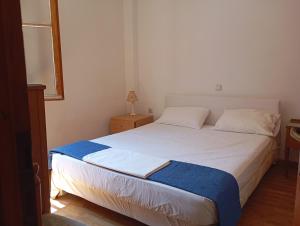 a bedroom with a large white bed with a blue blanket at Dafnis beach house in Karavostamo
