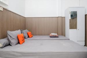 a bed with two orange pillows on top of it at Omah Ninten Syariah Laweyan RedPartner in Solo