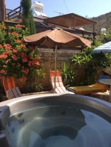an outdoor hot tub with chairs and an umbrella at Kuća za odmor Kipar in Pissouri