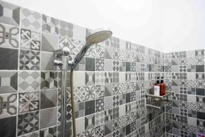 a shower in a bathroom with gray and white tiles at Omah Ninten Syariah Laweyan RedPartner in Solo +31 photos