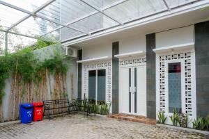 a glass house with two trash cans on a patio at Omah Ninten Syariah Laweyan RedPartner in Solo