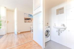 a white bathroom with a washing machine and a sink at Stadtwohnung im Zentrum in Größing