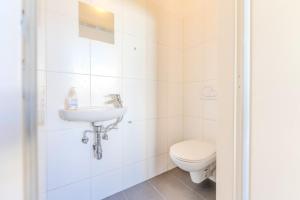 a white bathroom with a toilet and a sink at Stadtwohnung im Zentrum in Größing +29 photos