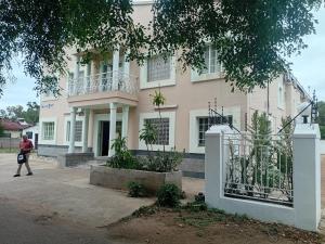 a person walking in front of a pink building at Brackendene Lodge in Gaborone