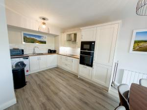 a kitchen with white cabinets and black appliances at Luxury 2-Bedroom Apartment Overlooking the Beach in Bundoran