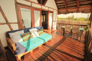 a screened in porch with a couch and a table at Cottage sur la mer in Vilanculos