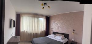 a bedroom with a bed and a large window at KM 0 one RESIDENCE in Piatra Neamţ