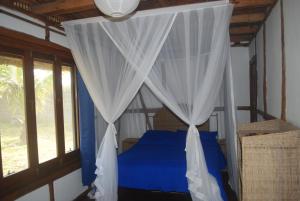 a bedroom with a blue bed with white curtains at Cottage sur la mer in Vilanculos