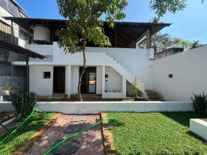 a white house with a tree in the yard at Hostel Akeeka in Alleppey