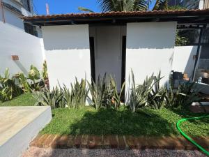 a garden in front of a house with a hose at Hostel Akeeka in Alleppey +2 photos