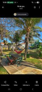 a picnic table and a hammock next to a palm tree at Pousada A Vida é Bela in Águas Belas