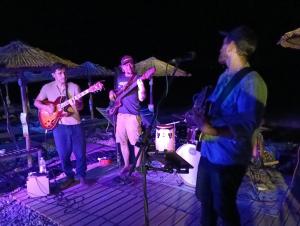 a group of three men playing music on a stage at Phil Samosflats Beachfront Maisonettes in Potokáki +54 photos