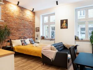 a bedroom with a brick wall and a bed and a couch at Apartamenty Bydgostia Dworzec in Bydgoszcz