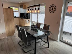 a dining room table with chairs and a clock on the wall at Barrierefreie Ferienwohnung Morgentau in Pewsum, 1 - 4 Personen in Krummhörn