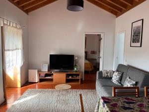 a living room with a couch and a flat screen tv at Quintinha da Chinela in Porto Judeu