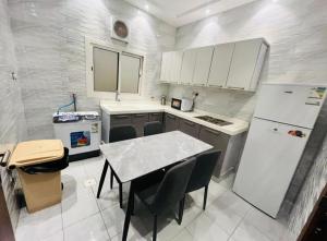 a small kitchen with a table and a refrigerator at فندق صها in Ash Shishah