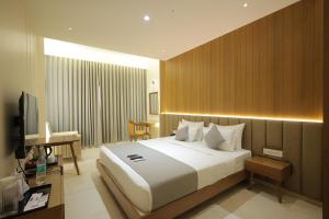 a bedroom with a large white bed and a desk at SUNDHA HOTEL palanpur in Pālanpur