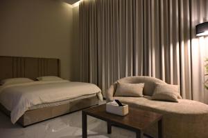 a bedroom with a bed and a chair and a table at شقق وغرف الرصف in Hail
