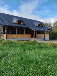 a building with a black roof on a field of grass at Wild-Traditional Bucovina in Câmpulung Moldovenesc