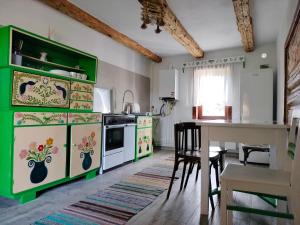 a kitchen with green and white cabinets and a table at Wild-Traditional Bucovina in Câmpulung Moldovenesc