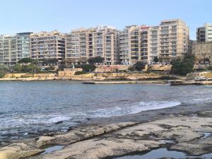 a view of a beach with buildings in the background at Тhree bedroom house "TEA" -with garage close to the sea -SLIEMA in Sliema