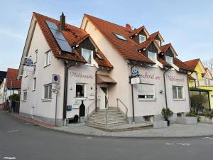 a white building with a red roof on a street at Landhotel am Mühlenwörth in Tauberbischofsheim