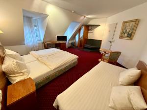 a hotel room with two beds and a television at Landhotel am Mühlenwörth in Tauberbischofsheim