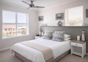 a bedroom with a large white bed with two windows at Deja View in Knysna