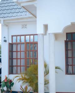 a white house with red windows and plants at Arusha 2bedroom in Arusha +6 photos