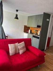 a red couch in a living room with a kitchen at Cooles Apartment an der Kathedrale in Fribourg +14 photos
