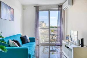 a living room with a blue couch and a balcony at Bright & Spacious 3 Bedroom Apartment close to Marsaskala seafront in Marsaskala