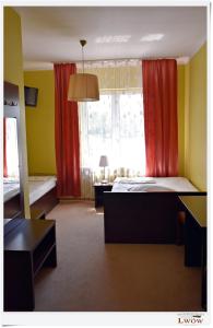 Habitación con 2 camas y ventana con cortinas rojas. en Lwów en Chełm